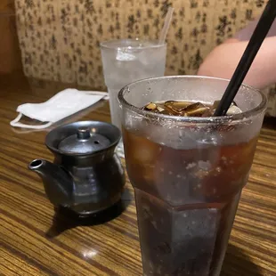 a glass of iced coffee and a teapot