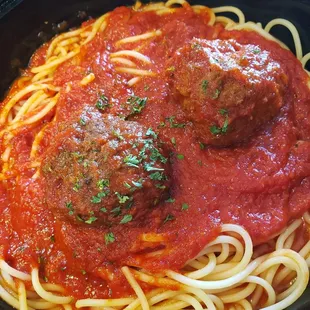 A hearty bowl of spaghetti and meatballs, garnished with fresh herbs and a rich tomato sauce from Genova's To Go.