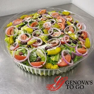 A large catering salad bowl made by Genova's To Go including fresh onions, tomatoes, peppers, parmesan cheese, etc.