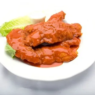 Delicious buffalo tenders on a plate, drizzled with sauce and topped with fresh lettuce from Genova&apos;s To Go.