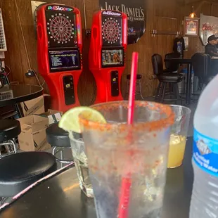 Tonic on ice with tajín rim, double tequila shot with pineapple back, and a bottled water. 2 dart games in the background