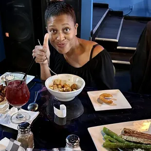 a woman sitting at a table with a bowl of food