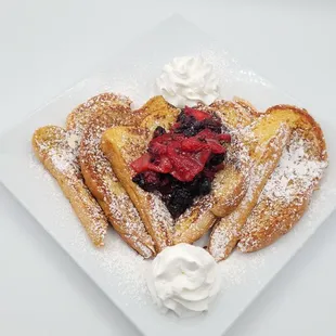 a plate of french toast with berries and whipped cream