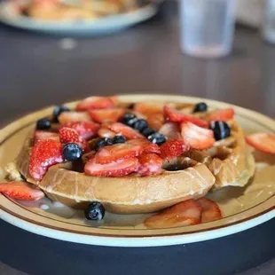 a plate of waffles with strawberries and blueberries