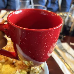 a slice of pizza and a red mug