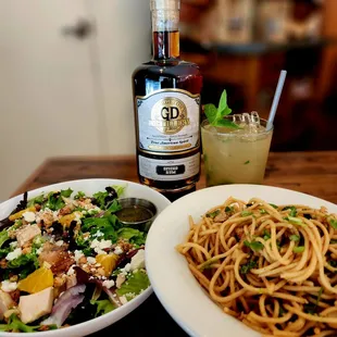 two plates of pasta and a bottle of gin