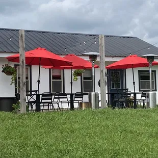 the outside of a restaurant with red umbrellas