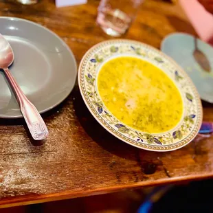 a bowl of soup and a spoon on a wooden table