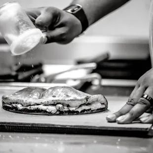  a person sprinkling salt on a sandwich