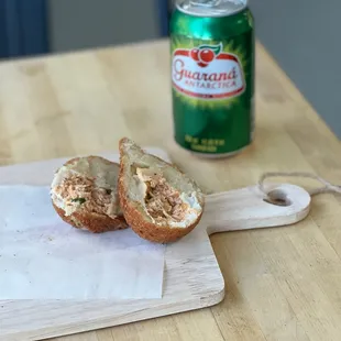 a bagel on a cutting board next to a can of beer