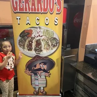 a little girl standing in front of a sign