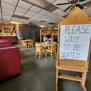 a sign saying please wait to be seated