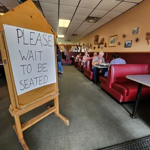 a sign saying please wait to be seated