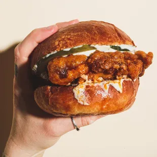 a hand holding a fried chicken sandwich