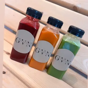 three bottles of juice on a bench