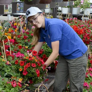 a woman picking flowers in a garden center