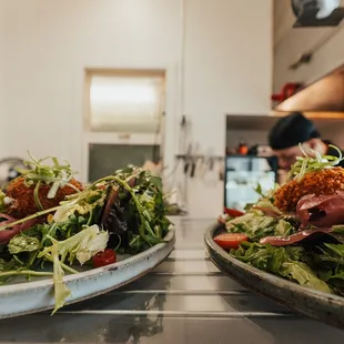 two plates of salad on a counter