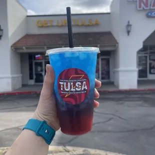 a hand holding a blue drink