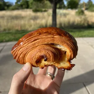 a hand holding a croissant