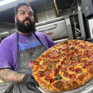 a man holding a large pizza