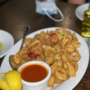 a plate of fried calamails with a side of tomato sauce