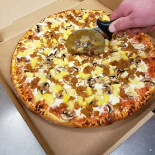a person cutting a pizza with a pizza cutter