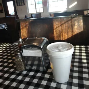 a bucket of hotdogs and a hot dog on a checkered table