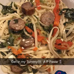 a plate of pasta with sausage and spinach