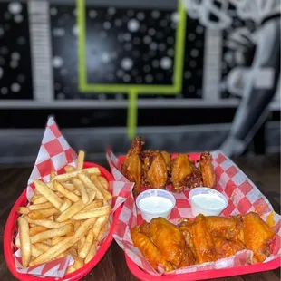 two baskets of chicken wings and french fries