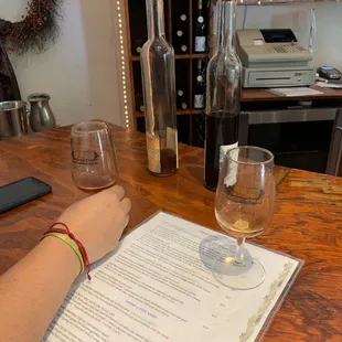 a person sitting at a table with wine glasses and a menu