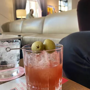 a glass of wine and two green olives