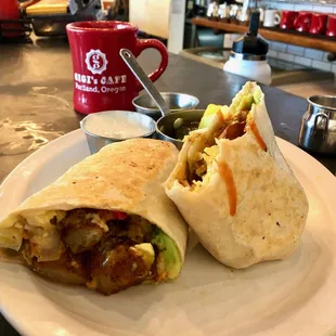 Grilled breakfast burrito served with sour cream and salsa verde on the side