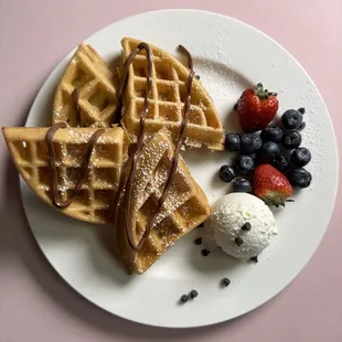 Waffle with strawberries blueberries and a scoop of ice cream