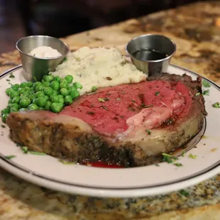 a plate of meat, mashed potatoes and peas
