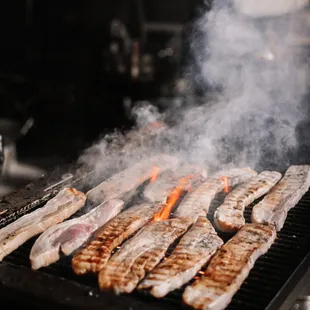 a lot of meat cooking on a grill