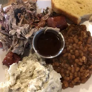 a plate of food with beans, bread, coleslaw and coleslaw