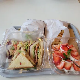 two trays of sandwiches and strawberries