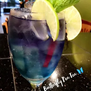 a blue drink with a lime slice