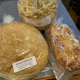 Noodles, sourdough round loaf, and jalapeño garlic cheese bread