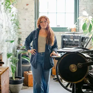 Lindsay, letterpress artist &amp; owner next to her antique printing press in her studio.