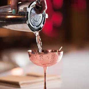 a person pouring a drink into a glass