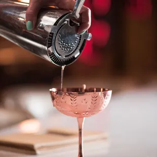 a person pouring a drink into a glass