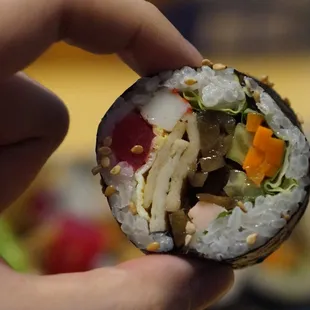 a hand holding a piece of sushi