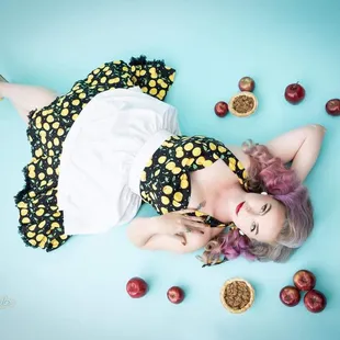 a woman laying on the ground surrounded by cherries