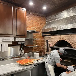 a man putting pizza into the oven