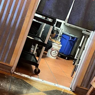 Pan of meat sitting on a bucket near a trash can