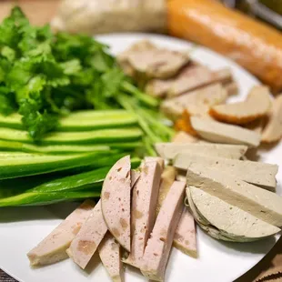 a plate of sliced meat and vegetables