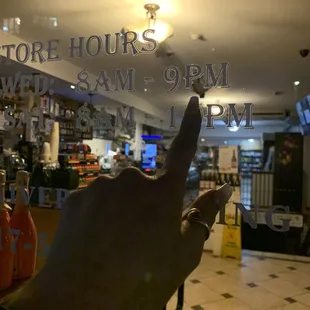 a hand pointing at the store hours window