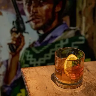 a glass of old fashioned cocktail with a slice of lemon