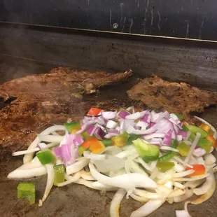 a steak and vegetables cooking on a grill